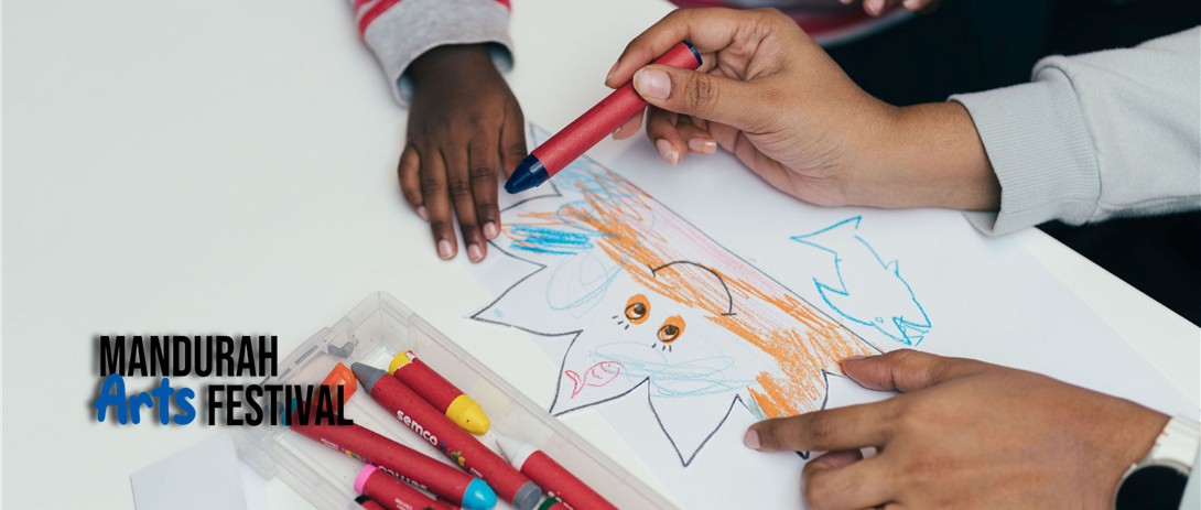 Two pairs of children's hands are colouring in a picture together while leaning on a white table